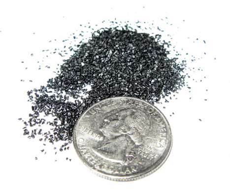 Black powder for muzzleloading rifles and pistols in FFFG granulation size. Quarter (diameter 24 mm) for comparison.