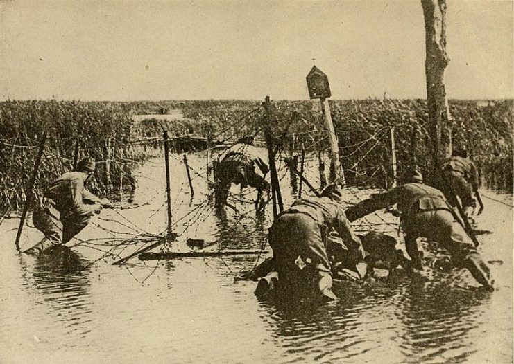 French soldiers struggle to pass multiple lines of barbed wire.1919