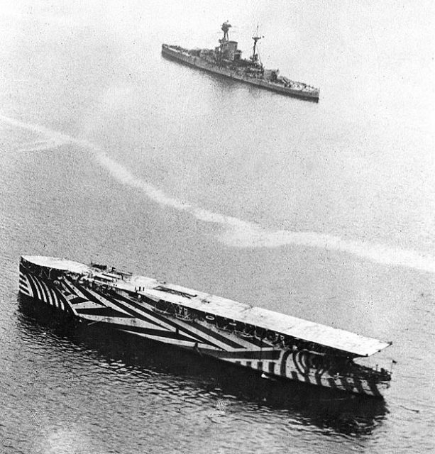 Argus in harbor in 1918, painted in dazzle camouflage, with a Revenge-class battleship in the background.