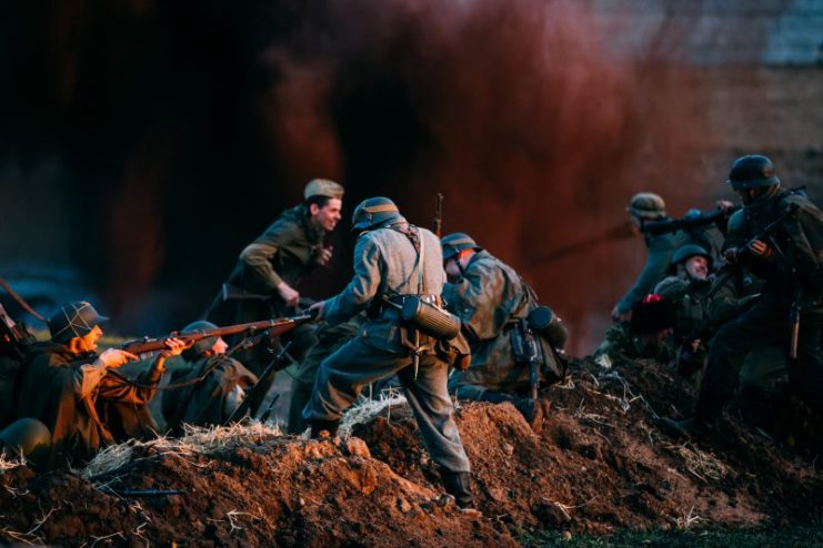 Re-enactors Dressed As German Wehrmacht Infantry Soldiers And Russian Soviet Soldiers World War II Play A Scene About Fighting In Trenches.