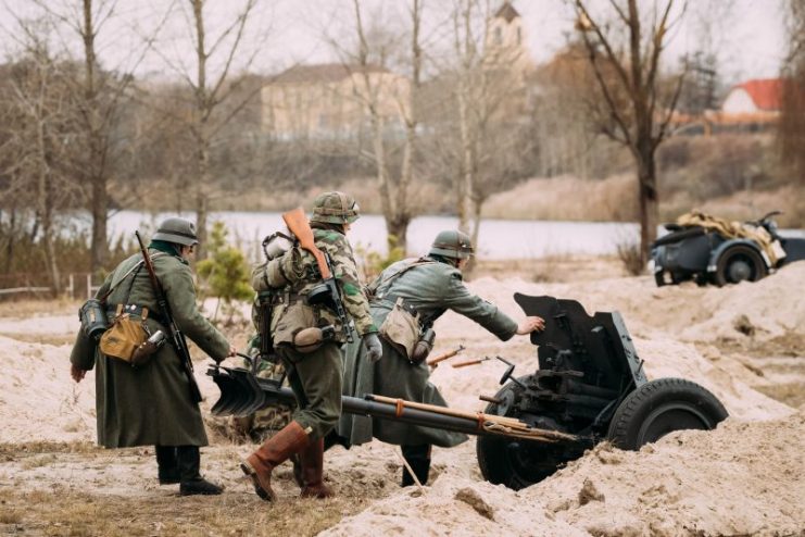 Gomel, Belarus – November 26, 2016: Re-enactors Dressed As German Wehrmacht Soldiers In WWII Roll Out Cannon At Firing Position.celebration Of 73rd Anniversary Of Liberation Of Gomel From Nazi Invaders