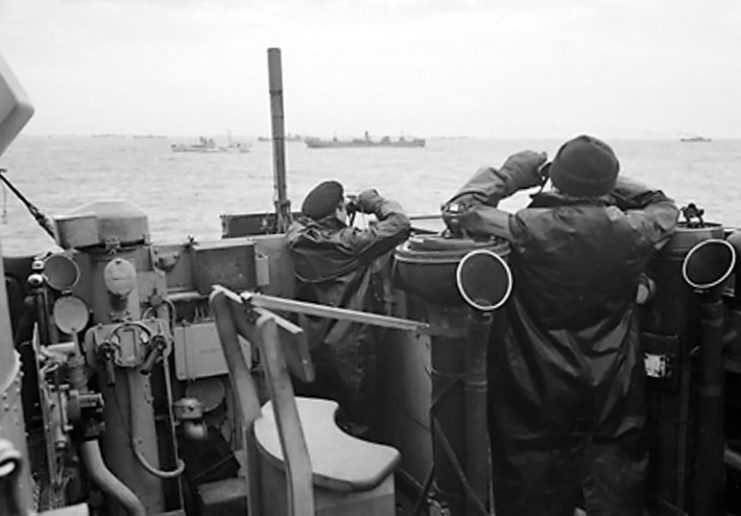Officers on the bridge of a destroyer, escorting a large convoy of ships keep a sharp look out for attacking enemy submarines during the Battle of the Atlantic.
