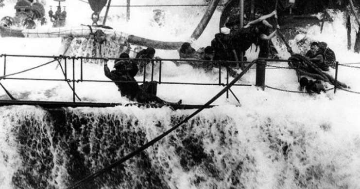 A wave breaks over the main deck, engulfing hose crew, as Neosho (AO-23) refuels Yorktown (CV-5) early in May 1942, shortly before the Battle of Coral Sea