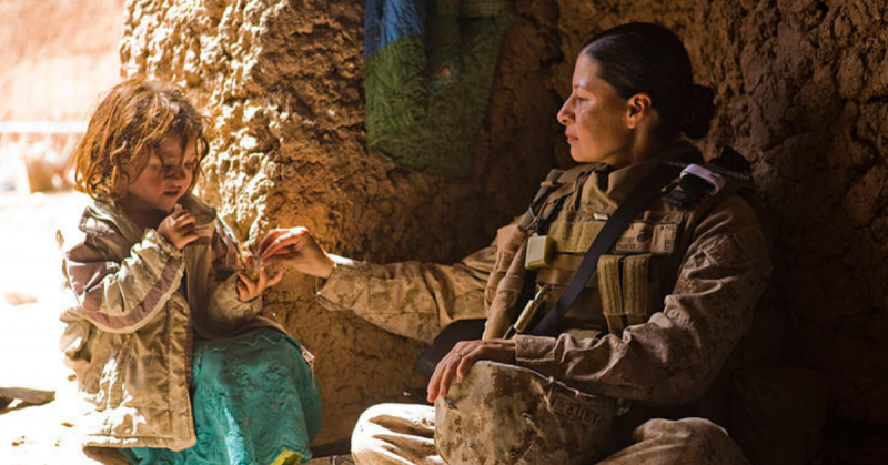 U.S. Marine Corps 1st Sgt. Raqual Painter gives candy to an Afghan girl while the girl's mother receives medical attention from U.S. Navy Lt. Michelle Lynch as part of a medical outreach program in the village of Now Abad in Helmand province, Afghanistan, on March 15, 2010