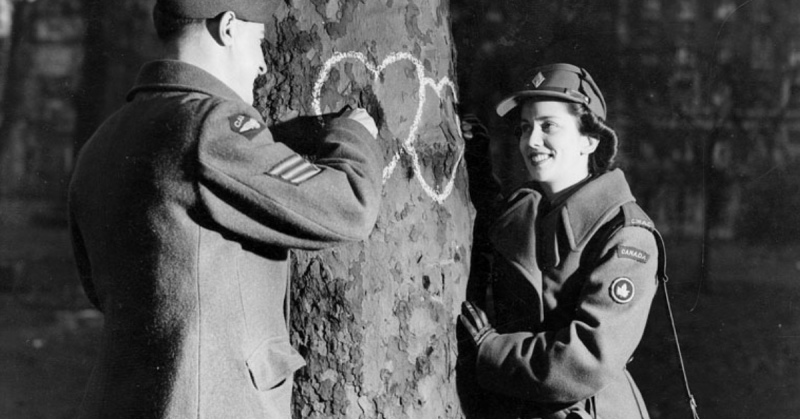 Young couple chalking hearts onto a tree during the war