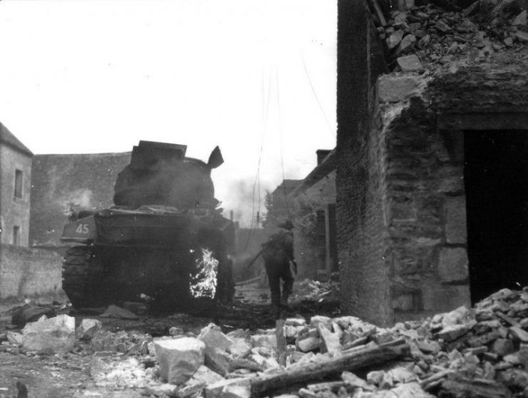 Soldier of 4th Canadian Armoured Division passing a destroyed Canadian tank in St. Lambert sur Dive