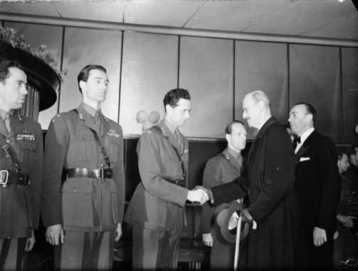 HM King Haakon VII of Norway at the premiere of the film Kampen om tungtvannet (Operation Swallow: The Battle for Heavy Water) at Klingenberg kino in Oslo. From the left: Knut Haukelid, Joachim Rønneberg, Jens Anton Poulsson shaking hands with the king, Kasper Idland. Photo: Leif Ørnelund / CC BY-SA 4.0