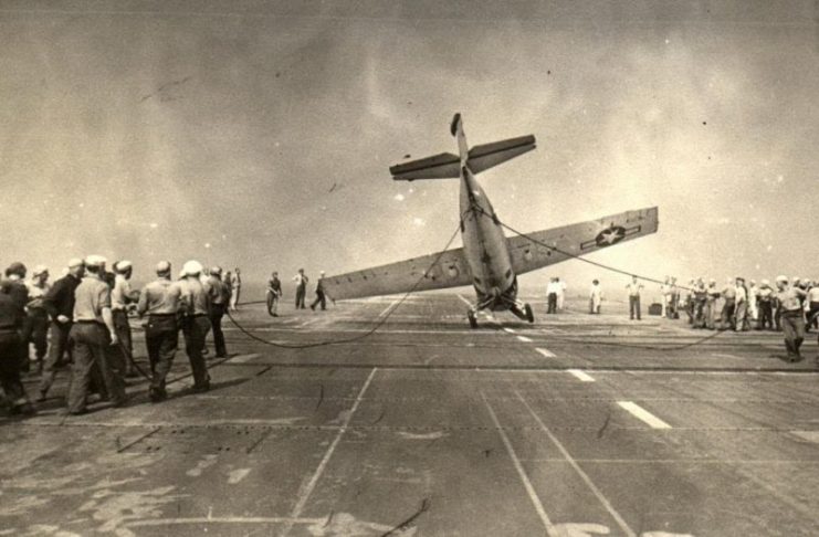 Deck crews aboard the training aircraft carrier USS Sable man lines to right an FM-2 Wildcat that had nosed completely over. Lake Michigan, United States, 1943-45