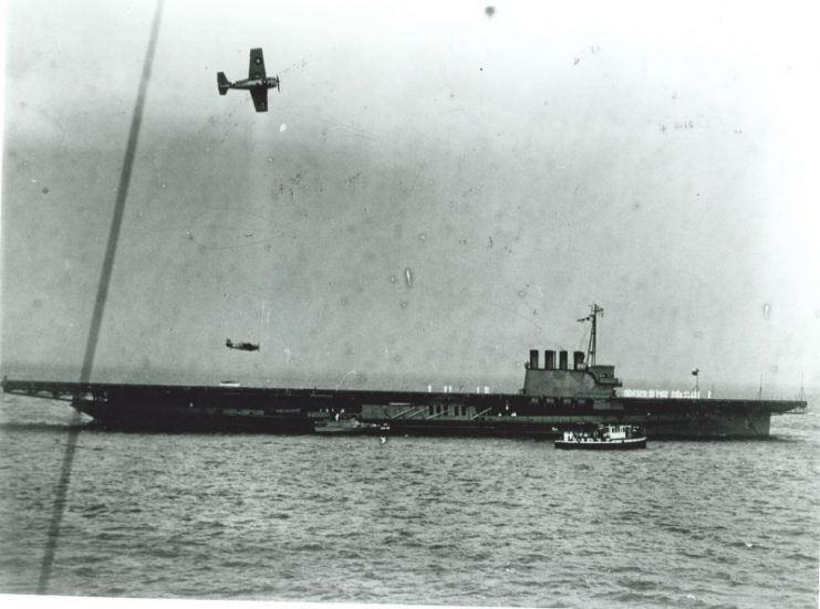 One F4F Wildcat flies overhead as another makes a low altitude pass over the flight deck of the training aircraft carrier USS Wolverine as she lies at anchor on Lake Michigan, Chicago, Illinois, United States, 1943.