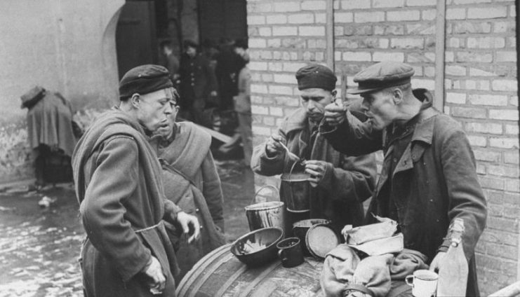 Russian men freed from a Nazi POW slave labor camp eat bread and molasses from a cask outside a looted liquor store after their liberation by advancing Allied troops. Photo: Kristine CC BY-NC 2.0