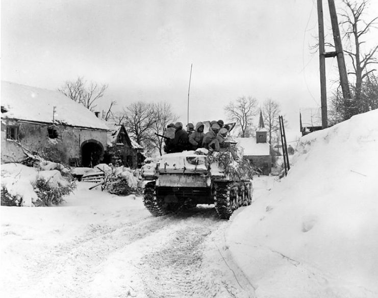 Members of Company I, 3d Battalion, 16th Infantry Regiment, 1st Division, U.S. First Army, ride on a tank, during an advance (in the battle of the Bulge) January 1945.