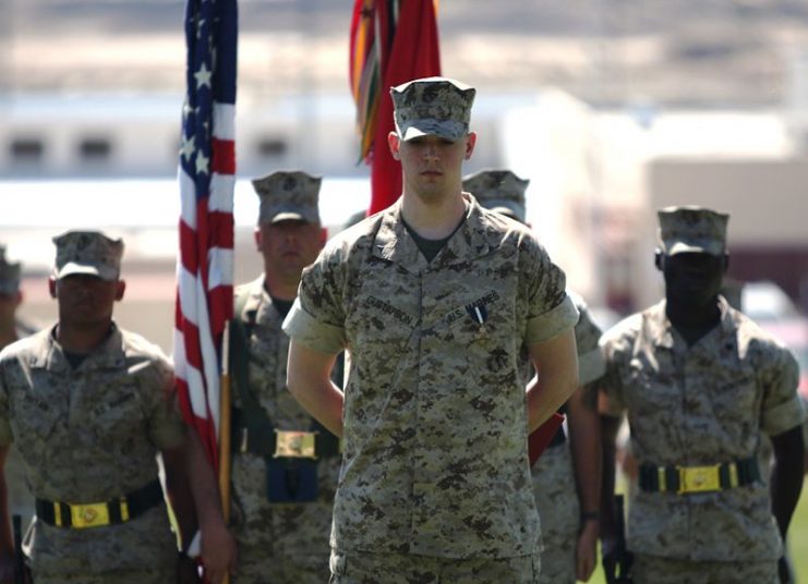 Lance Cpl. Brady Gustafson, a machine gunner with Golf Company, 2nd Battalion, 7th Marine Regiment, stands in from of the battalion at perfect parade rest, despite the amputation of his right leg below the knee. Gustafson received the Navy Cross and a meritorious promotion to corporal during a ceremony March 27 at Lance Cpl. Torrey Grey Field.