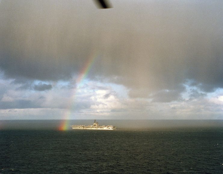A port bow view of the aircraft carrier USS FORRESTAL (CV 59) passing through a rainbow while underway in the North Atlantic Ocean during Exercise TEAM WORK’88.