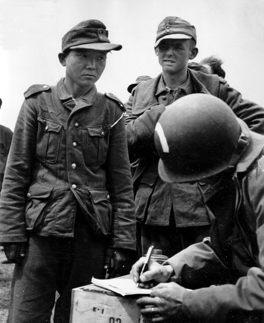 An unidentified man in Wehrmacht attire (left) following capture by American paratroopers in June 1944 after D-Day.