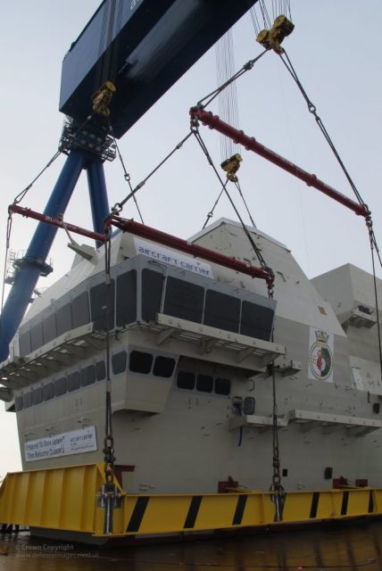 Bridge Section of HMS Queen Elizabeth Put into Place.The 700 tonne navigation bridge of the future aircraft carrier HMS Queen Elizabeth is lowered into place at Rosyth Shipyard in Scotland.Photo: Defence Images CC BY-NC 2.0