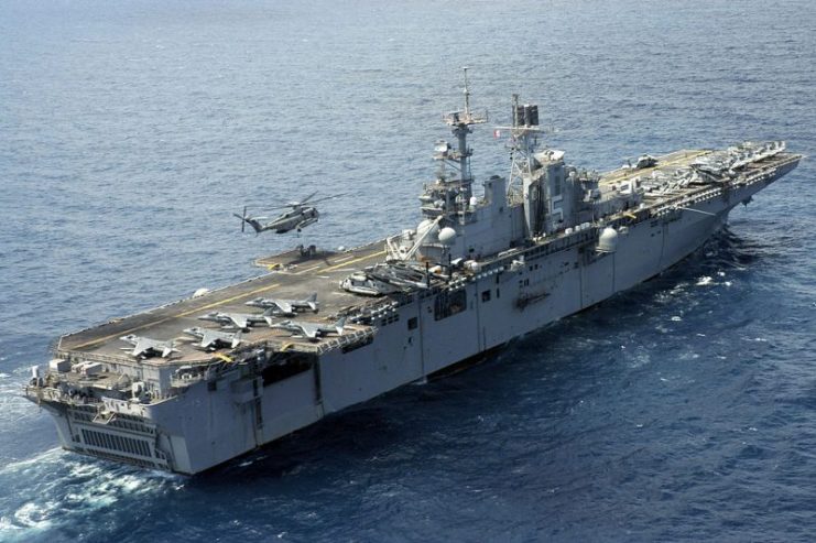 A CH-53E Super Stallion lifting pallets off USS Bataan.