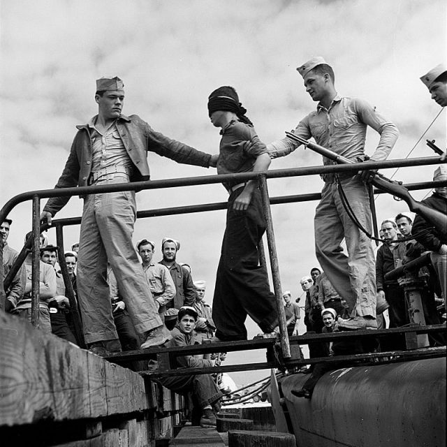 A Japanese POW being led off a US Navy submarine in May 1945.