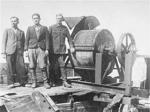 A Sonderkommando 1005 unit stand next to a bone crushing machine at the Janowska concentration camp