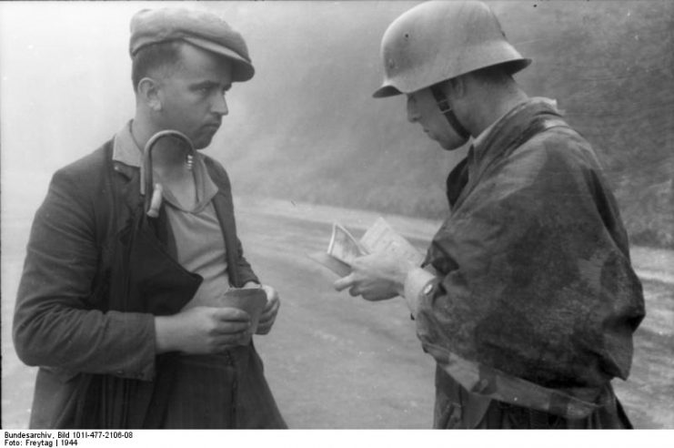 German soldier examining the papers of an Italian civilian outside of Milan, 1944. Photo: Bundesarchiv, Bild 101I-477-2106-08 / Freytag / CC-BY-SA 3.0