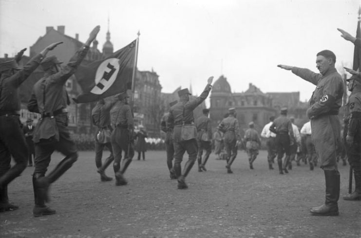 Nazi Party (NSDAP) leader Adolf Hitler saluting members of the Sturmabteilung. By Bundesarchiv – CC BY-SA 3.0 de