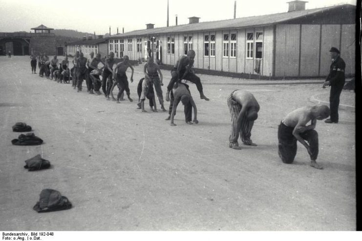 Gruelling and pointless physical exercise was one of the methods of “wearing the inmates down”.[36] Here a group of prisoners are forced to play “leap frog”.Photo: Bundesarchiv, Bild 192-048 / CC-BY-SA 3.0