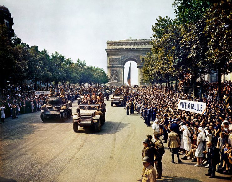 Crowds of French patriots line the Champs Elysees to view Free French tanks and half tracks of General Leclerc’s 2nd Armored Division passes through the Arc du Triomphe, after Paris was liberated on August 26, 1944. Among the crowd can be seen banners in support of Charles de Gaulle.