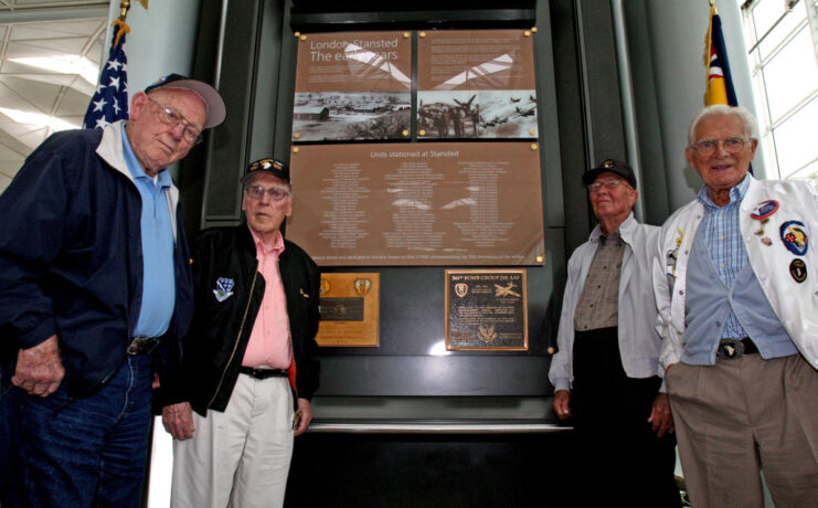 Lynn "Buck" Compton, Ed Tipper, Bradford Freeman and Donald Malarkey standing next to a memorial at Stansted Airport, Essex