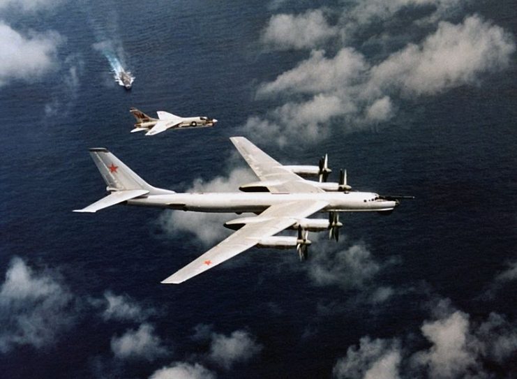 An F-8 Crusader intercepts a Tu-95 “Bear-D”. Oriskany, from which the F-8 launched, can be seen in the background.