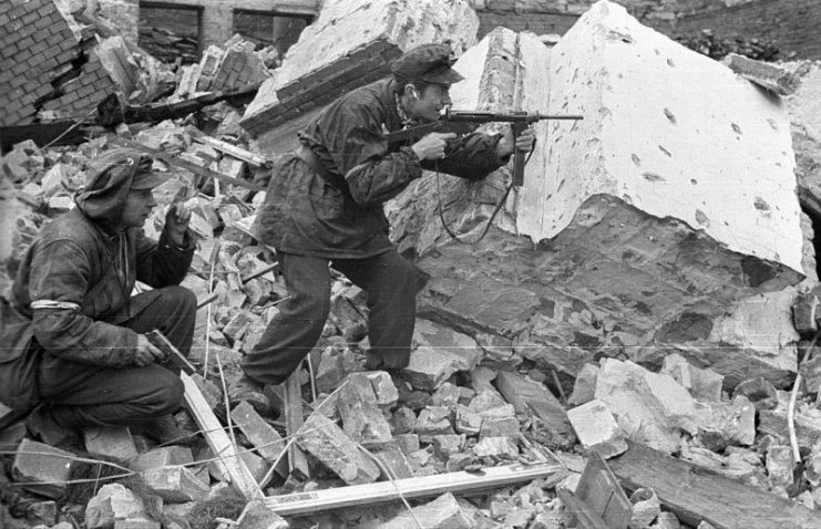 Home Army soldiers Henryk Ożarek “Henio” (left) holding a Vis pistol and Tadeusz Przybyszewski “Roma” (right) firing a Błyskawica submachine gun, from “Anna” Company of the “Gustaw” Battalion fighting on Kredytowa-Królewska Street, October 3, 1944.