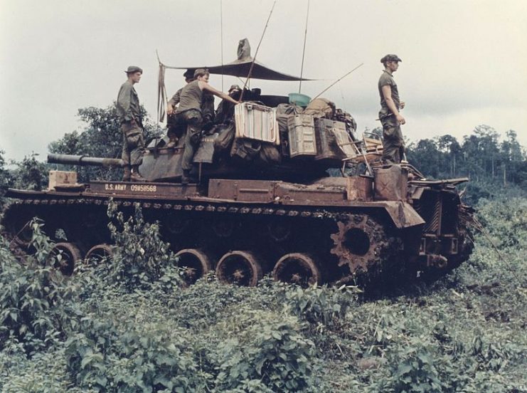 Men of Troop B, 1st Battalion, 10th Cavalry Regiment, 4th Infantry Division, and their M-48 Patton tank move through the jungle in the Central Highlands of Vietnam, June 1969