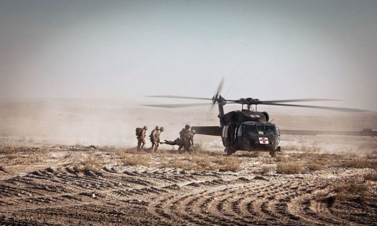 Petty Officer 3rd Class accompanies litter-bearers as they load an injured Marine into a UH-60 Black Hawk helicopter during a medical evacuation in Garmsir, in Afghanistan