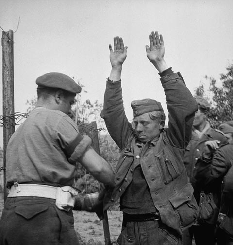 Canadian troops searching German prisoners during the early stages of Operation Totalize.