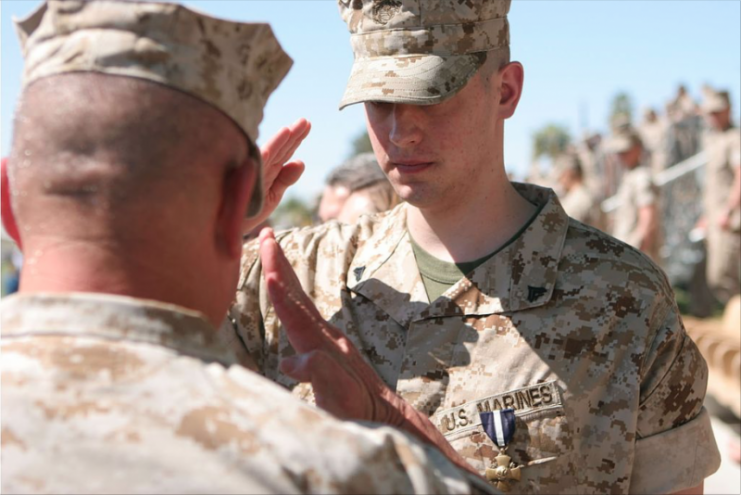 Corporal Brady A. Gustafson, renders a salute to one of the many 2nd Battalion, 7th Marine Regiment officers on hand to witness the awarding of the Navy Cross to Gustafson during a ceremony