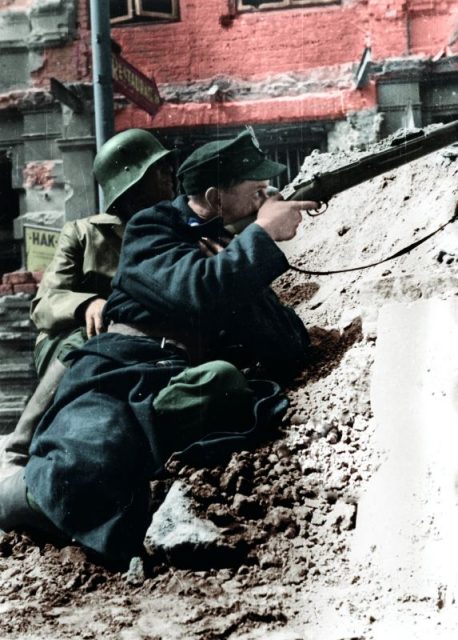 Soldier from the “Kiliński” Battalion pictured aiming his rifle at the German-occupied PAST building, August 20, 1944.