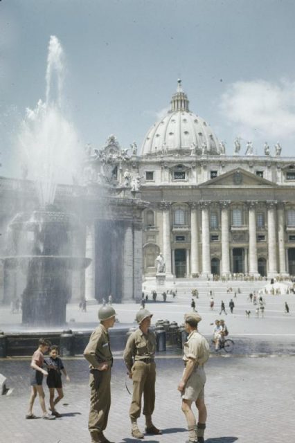 Two American soldiers talking to a British soldier beside one of the fountains in St Peter’s Square. In the background is the Cathedral.