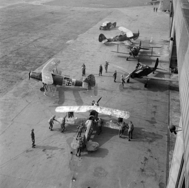 British troops inspecting abandoned German Gotha Go 145, and a solitary Arado Ar 96 training aircraft at Celle airport, April 13, 1945.