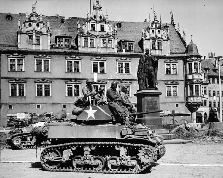 Crews of U.S. M5 Stuart light tanks from Company D, 761st Tank Battalion, stand by awaiting call to clean out scattered Nazi machine gun nests in Coburg, Germany.