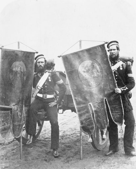 Company Sergeant William Christie and Sergeant Samuel McGifford, 4th Bn., Royal Artillery, with captured Russian banners which were brought back to England as war trophies, 1856.
