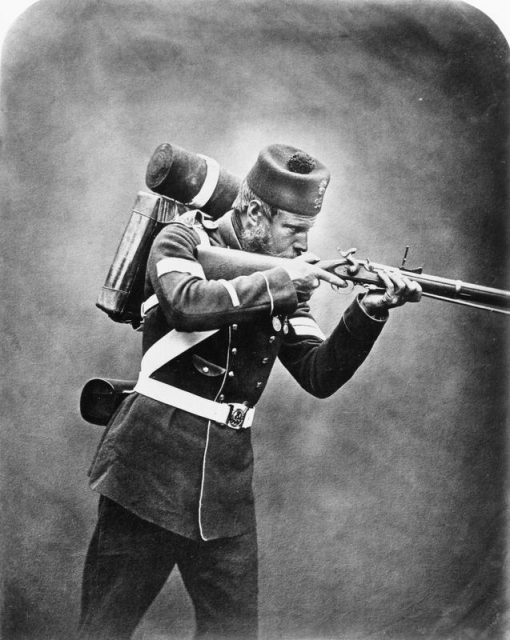 Portrait of Corporal James Tinn, 95th Regiment, wearing pack and aiming his rifle.