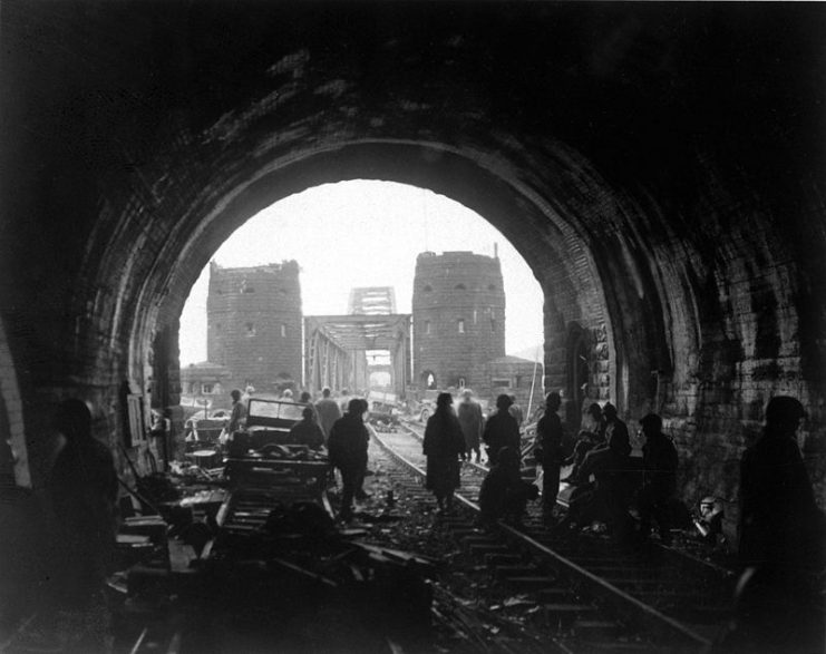First U.S. Army men and equipment pour across the Remagen Bridge, knocked out jeeps in foreground. Germany, 11 March 1945.