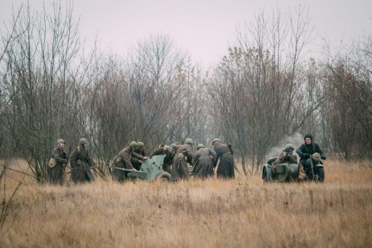 Soldiers of the Red Army deploy a cannon for battle in an autumn field. Reconstruction of a battle from WWII.