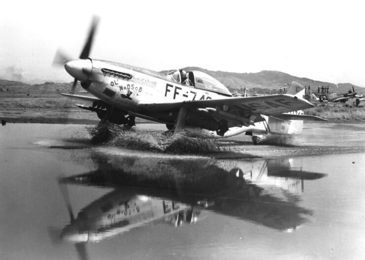 North American F-51 Mustang taxiing through a large puddle on the runway