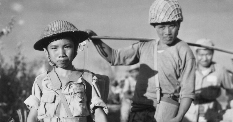 A Chinese Nationalist soldier, age 10, from the Chinese Army in India waiting to board a plane in Burma, May 1944
