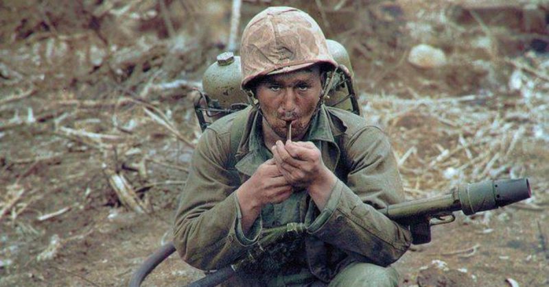 US Marine with an M2-2 flamethrower, lighting a pipe while gallons of gasoline and nitrogen are strapped to his back. Iwo Jima, February 1945. Colorized by Jecinci