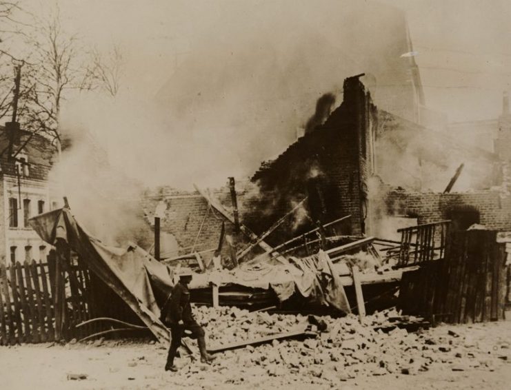 British soldier walking in front of the remains of a home.