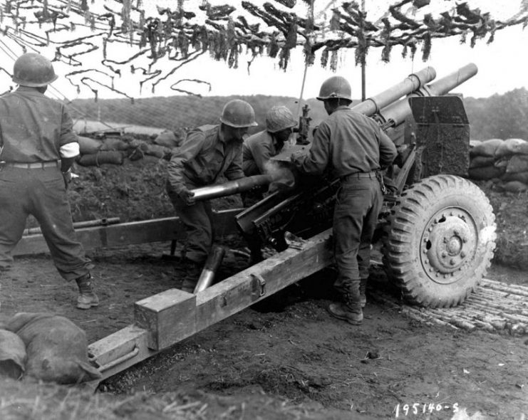A team of Japanese-American G.I.s from a Field Artillery Battalion throw 105mm shells at Germans in support of an infantry attack in Bruyères, France.
