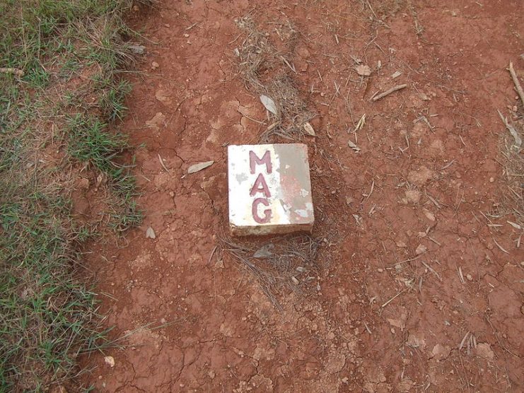 Markers placed by the Mines Advisory Group (MAG) after demining in the area around Phonsavan, Laos. The white side indicates the area that has been clear of unexploded ordnance (UXO), i.e. the safe side, and the red side indicates the area that has not yet been cleared.