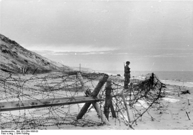 A German Soldier on a watch. A common sight on beaches of the Atlantic Wall, 1944. Bundesarchiv – CC-BY SA 3.0