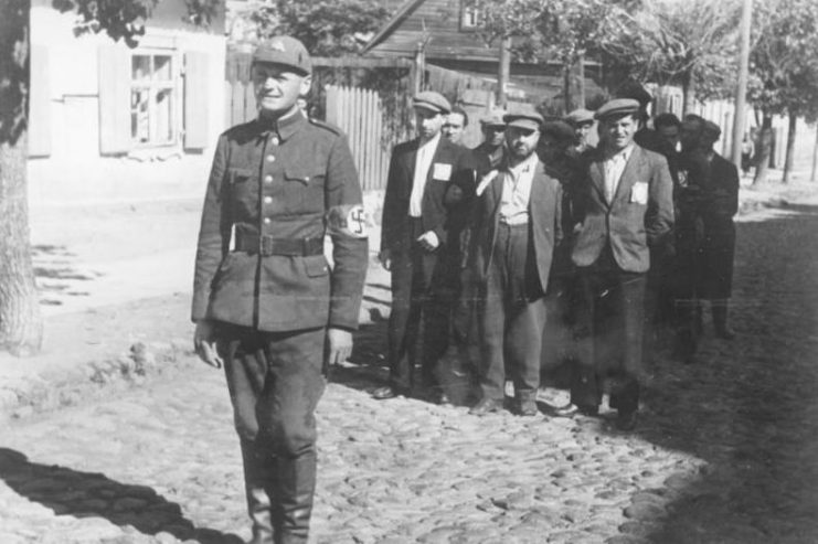 Lithuanian Nazi policeman with Jewish prisoners, July 1941. Photo: Bundesarchiv, Bild 183-B10160 / CC-BY-SA 3.0