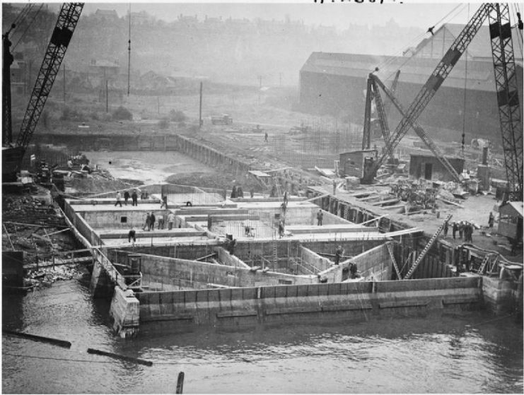 Sea forts in the Thames Estuary: A completed pontoon that will form the base of a sea fort to be used in the Thames Estuary. The first pre-assembled reinforcing grids of the twin towers are in place and the pontoon is lying on the mud in No 1 berth. Later it was floated on the tide to a dock basin. These secret forts were an effective defence against attacks by sea and air on the estuary.